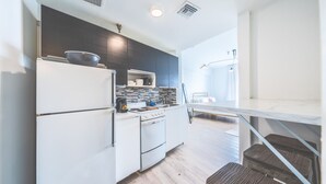 Een moderne keuken met witte apparaten, donkere kastjes en een betegelde achterwand.