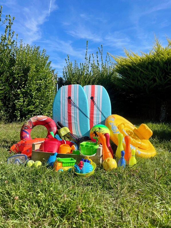 Uma área gramada com diversos brinquedos de praia e itens infláveis, incluindo uma bola de praia e um flutuador.