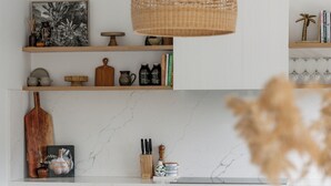 A modern kitchen with white cabinetry, a marble backsplash, and a central island with bar stools.