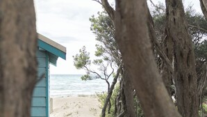 A beach house with a staircase leading to a sandy beach.
