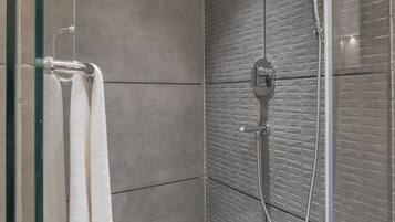 A modern shower with a glass door, a towel rack, and a showerhead.