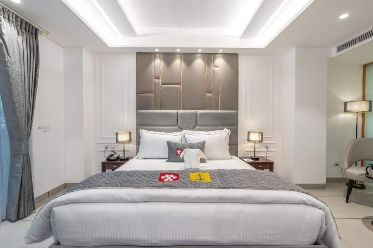 A modern hotel room with a large bed, bedside tables, a desk, and a chair.