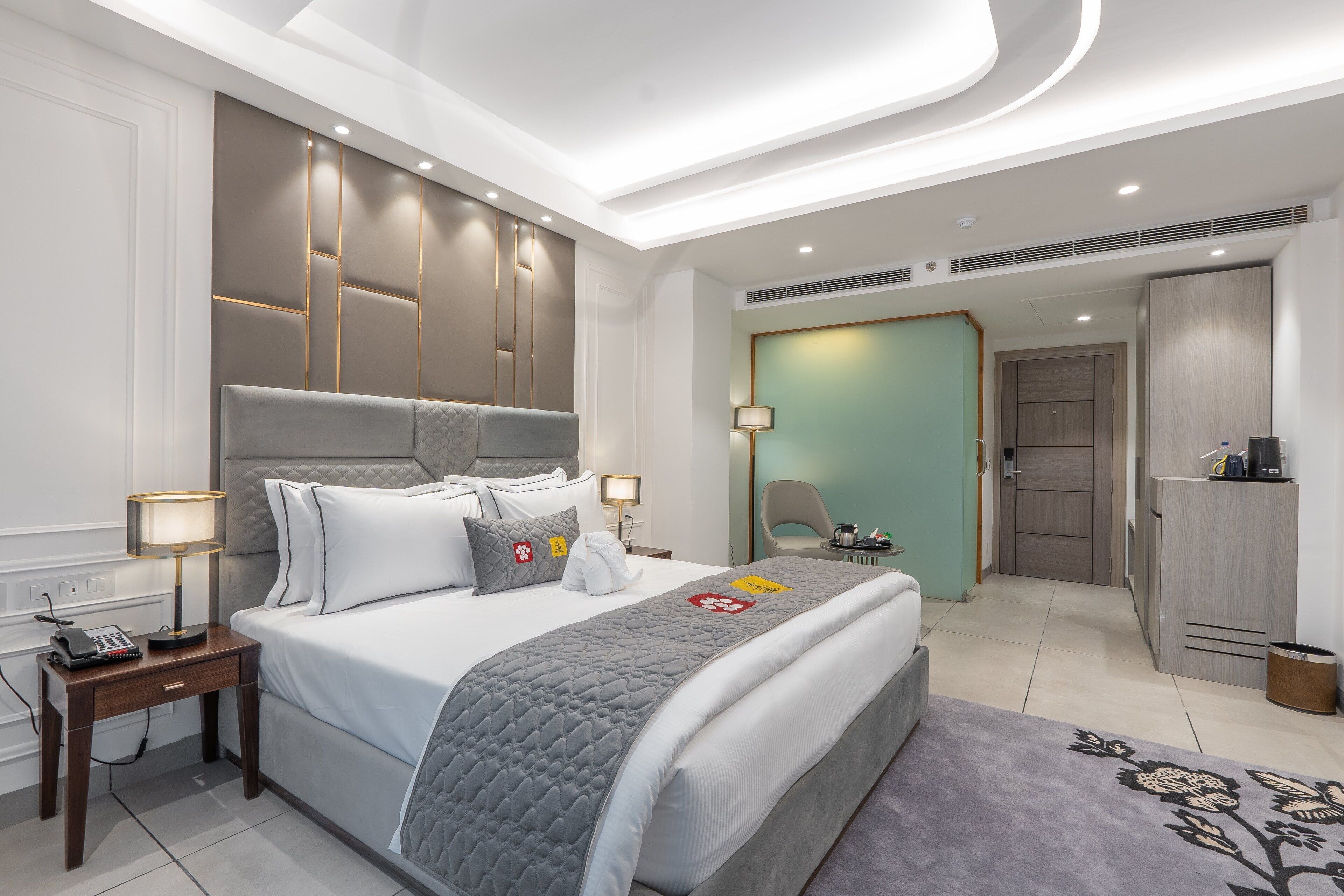 A modern hotel room with a large bed, bedside lamps, a desk, and a wardrobe.