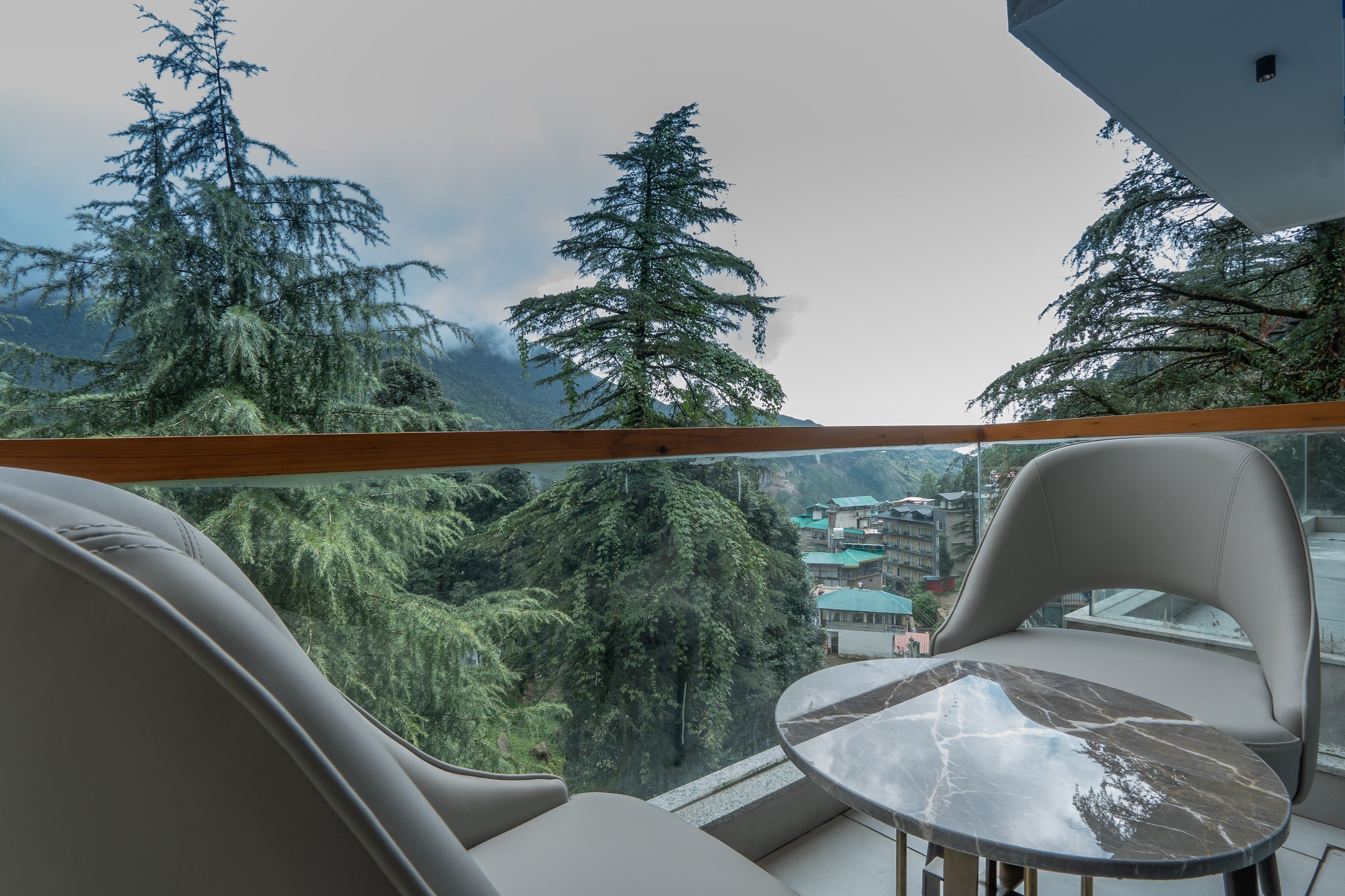 A balcony with a view of a mountainous landscape and a table with chairs.