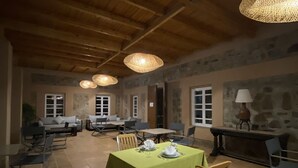 Un'area pranzo con un tavolo lungo apparecchiato per quattro persone, circondato da sedie. Sopra il tavolo, lampade a sospensione.