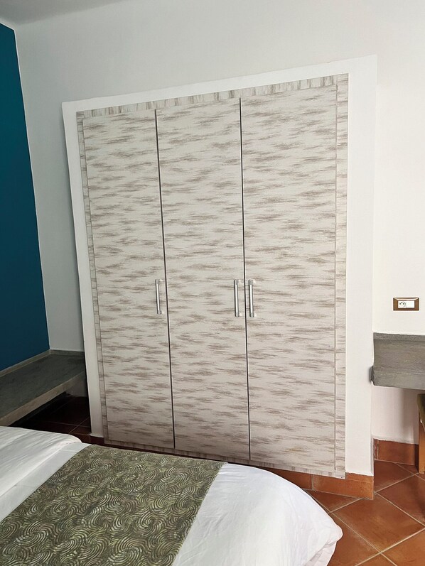 Ein Schlafzimmer mit einem Bett, einem Kleiderschrank, einem Waschbecken und einer blauen Wand.