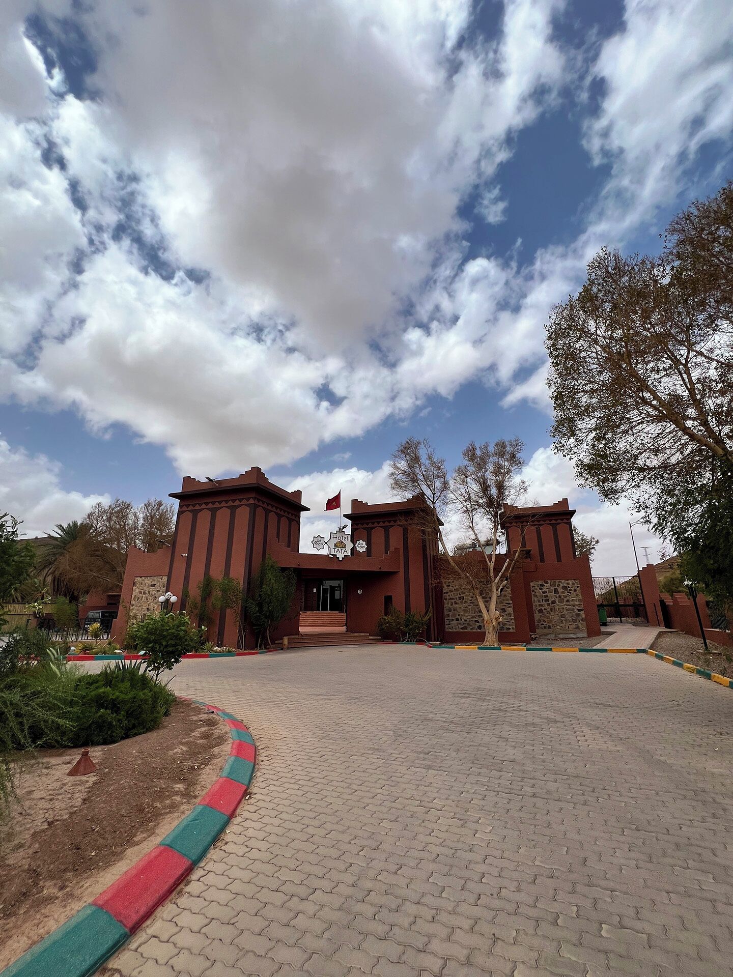 A hotel entrance with a brick facade, a flag, and a clear sky.