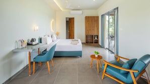 Una habitación de hotel moderna con cama, escritorio y silla, una mesita con planta y balcón con vistas.