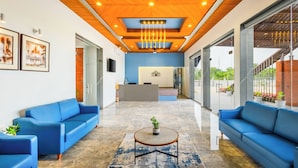 Un área de recepción moderna con sofás azules, una mesa de recepción y un ventilador de techo.
