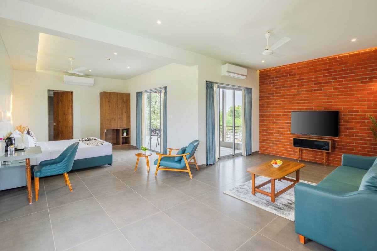 Uma sala de estar moderna com sofá, cadeiras, televisão e varanda com portas de correr.