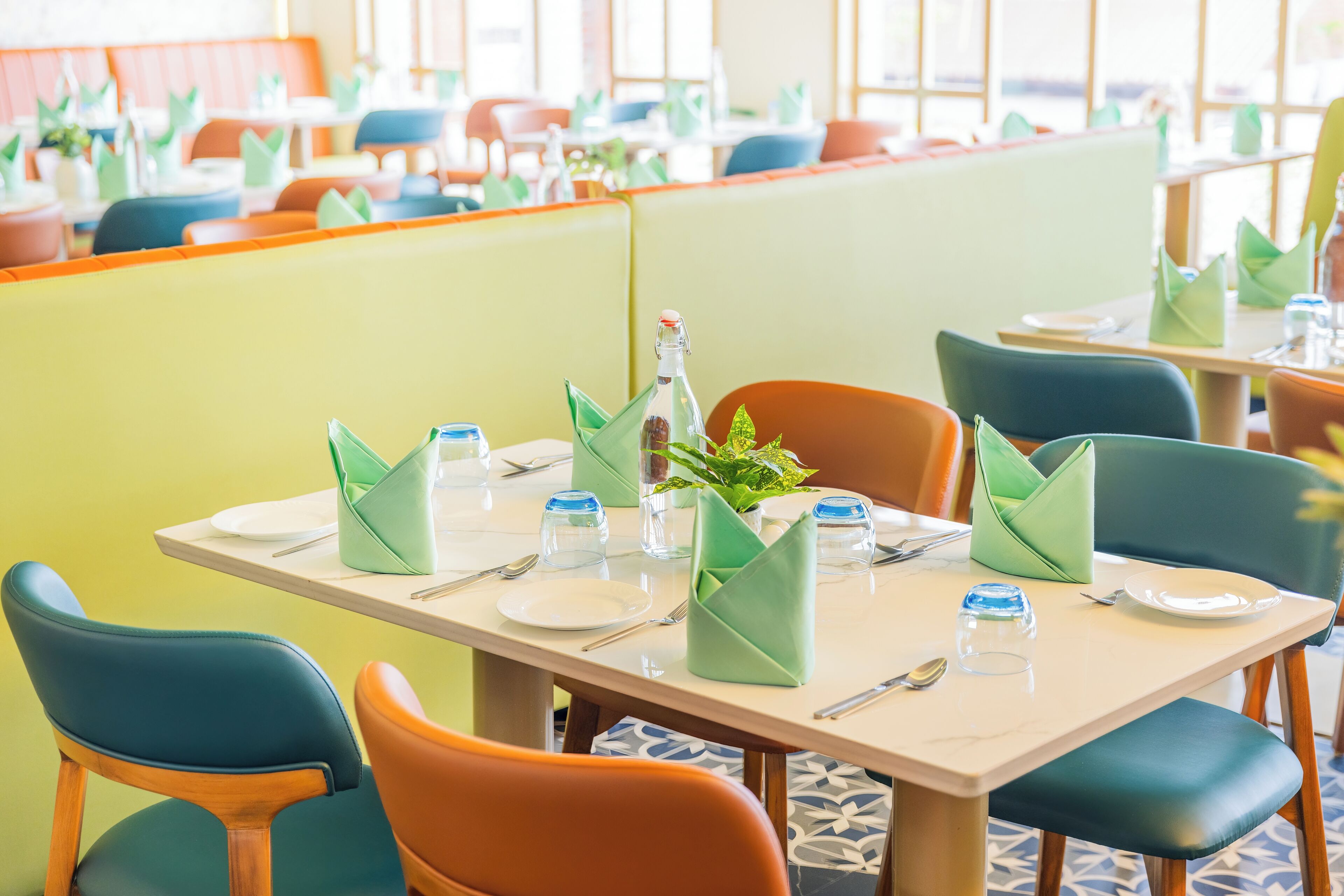 Ein Restaurant mit Sitzgelegenheiten in Form von Boxen und Tischen, jeweils mit Tellern, Besteck und Gläsern gedeckt.