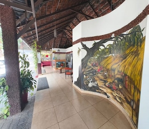 A hotel lobby with a tiled floor, a reception desk, and a mural of a tropical scene.