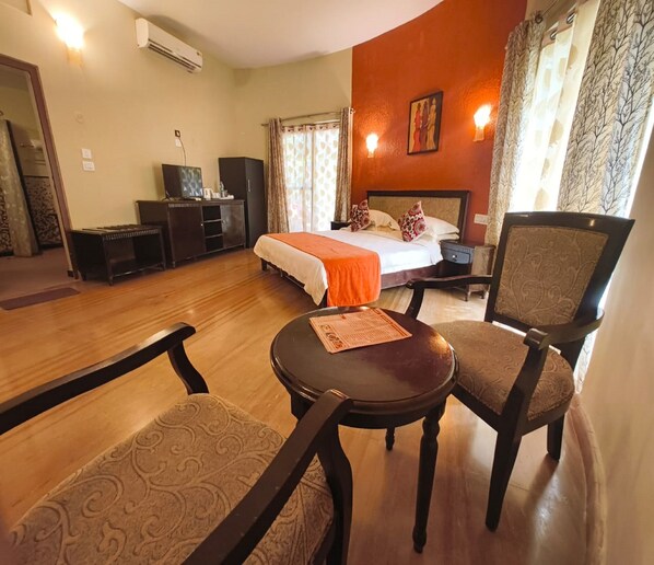 A hotel room with a bed, a desk, a chair, and a small table. - RiverRoost Resorts (Mangaluru)