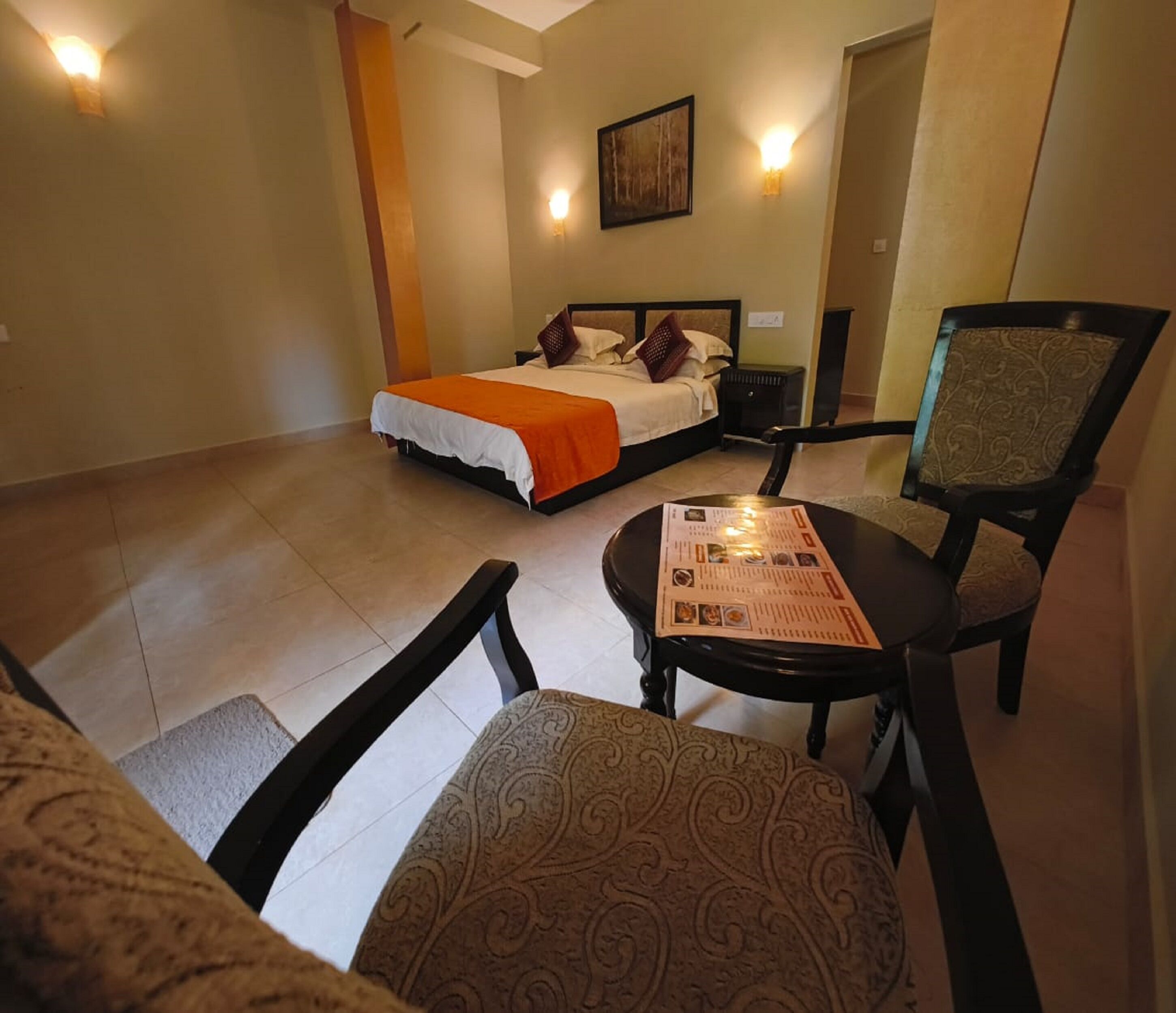 A hotel room with a bed, a table with a menu, and two chairs.