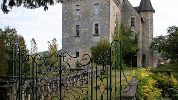 Un bâtiment historique en pierre, doté d’une tour et d’une porte ornée de ferronneries complexes.