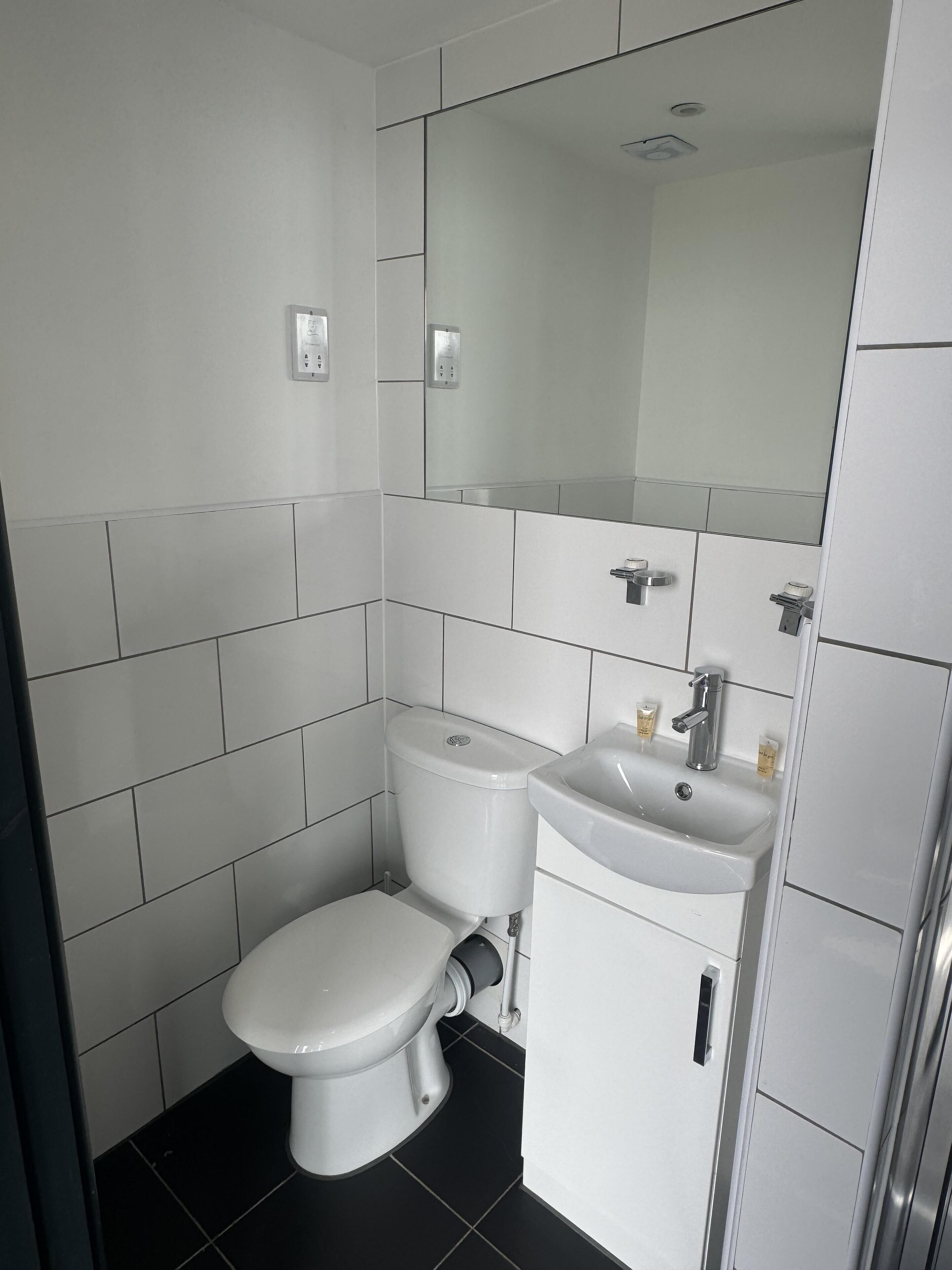Une salle de bain moderne avec des toilettes, un lavabo et un miroir.