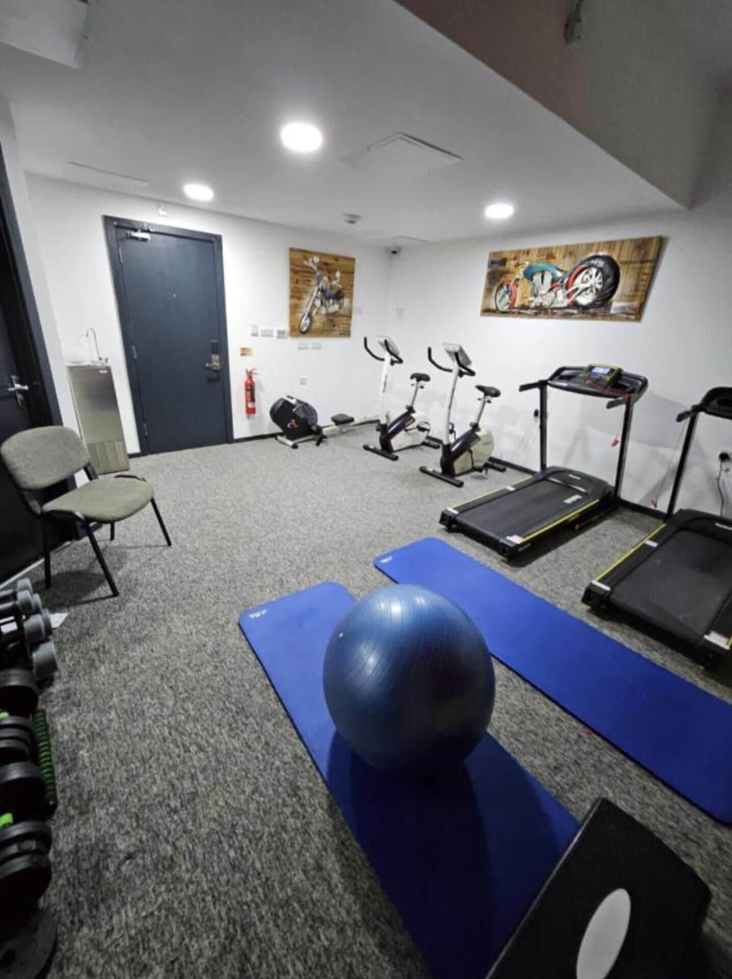 A gym with exercise equipment including treadmills, stationary bikes, and free weights.