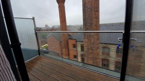 Un balcon donnant sur des immeubles en briques et des cheminées.