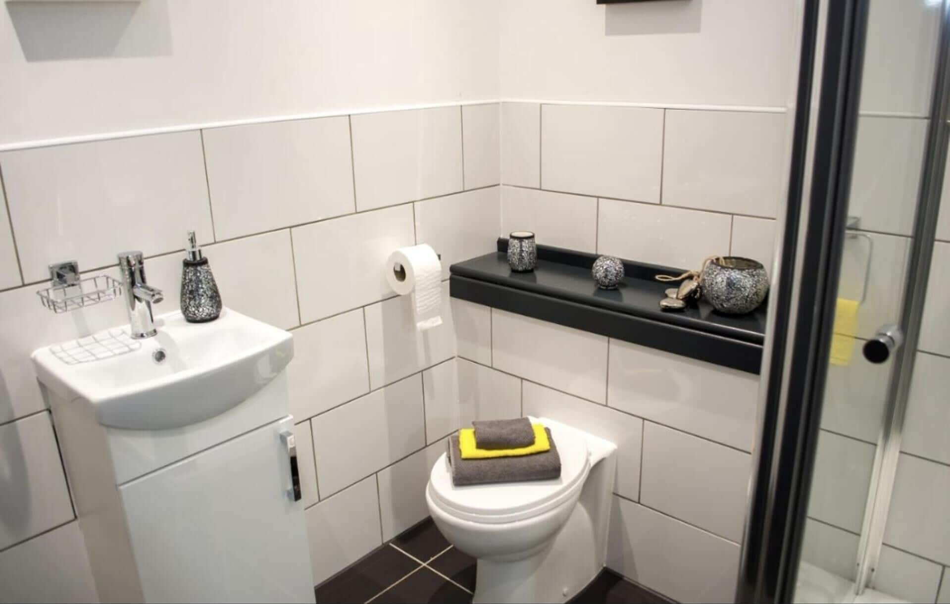 Et moderne badeværelse med hvid vask, toilet og bruseområde.