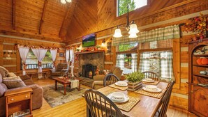Interior acolhedor de uma cabana de madeira com lareira, móveis de madeira e um espaço de jantar.
