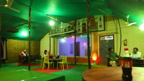 An indoor dining area with tables and chairs, ceiling fans, and a Coca-Cola bottle on a table. - Le Apex (Vanur)