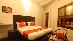 A hotel room with a bed, a nightstand, a table with a tray of flowers, and a chair. - Le Apex (Vanur)