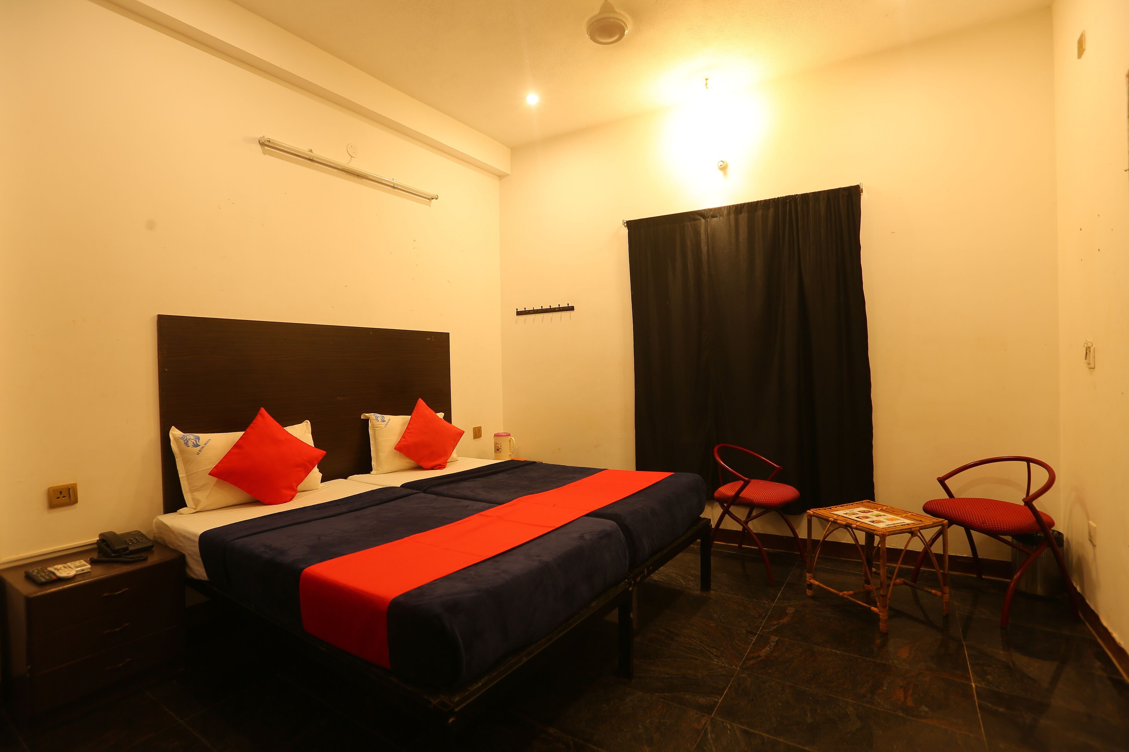 A hotel room with a bed, a bedside table, a chair, and a small table.