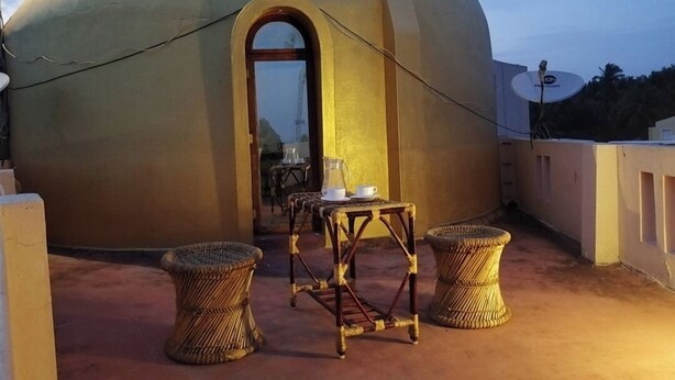 A dome-shaped building with a door and a table with chairs in front. - Le Apex (Vanur)