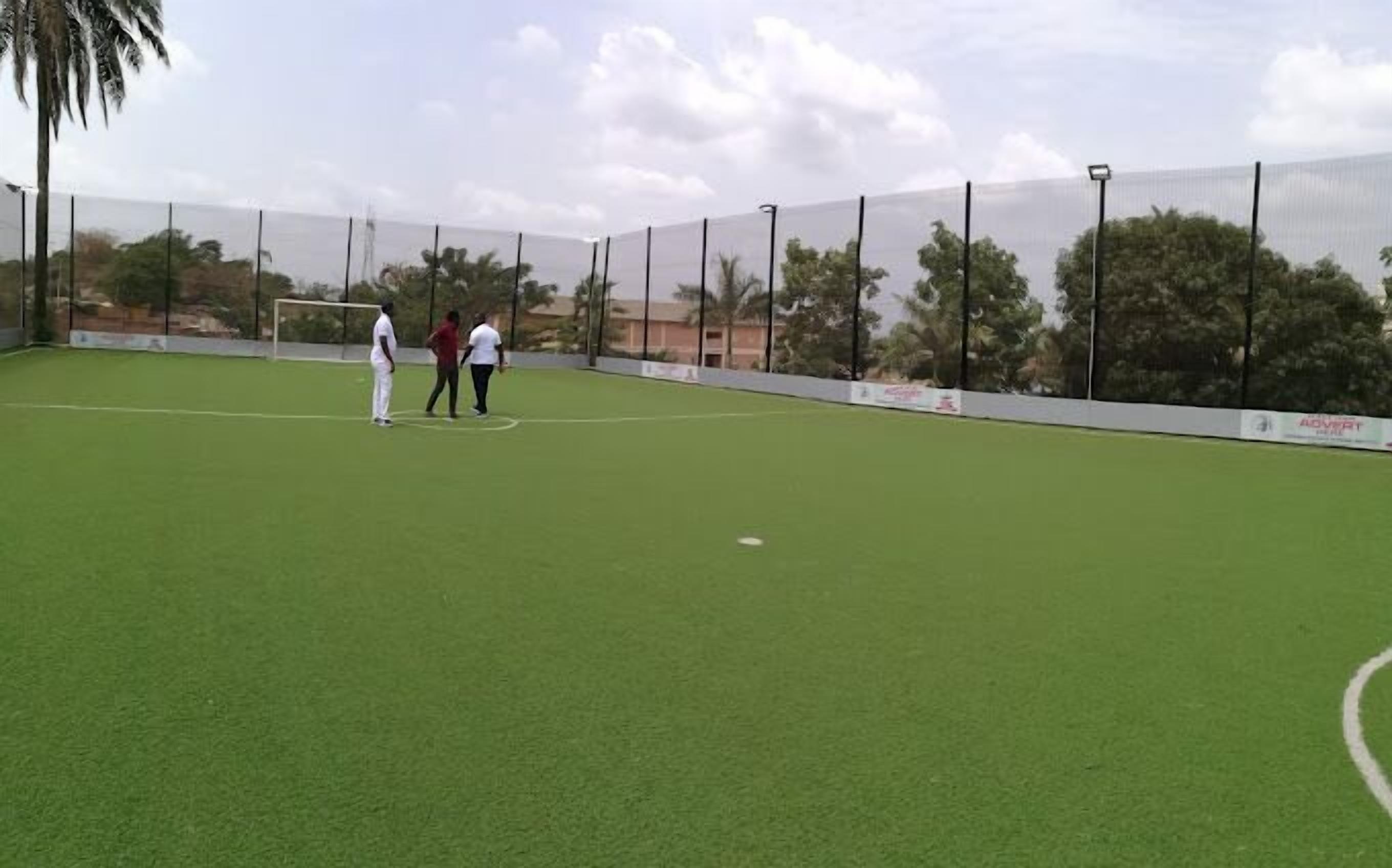 Un campo deportivo al aire libre con un arco, rodeado por una valla y árboles.
