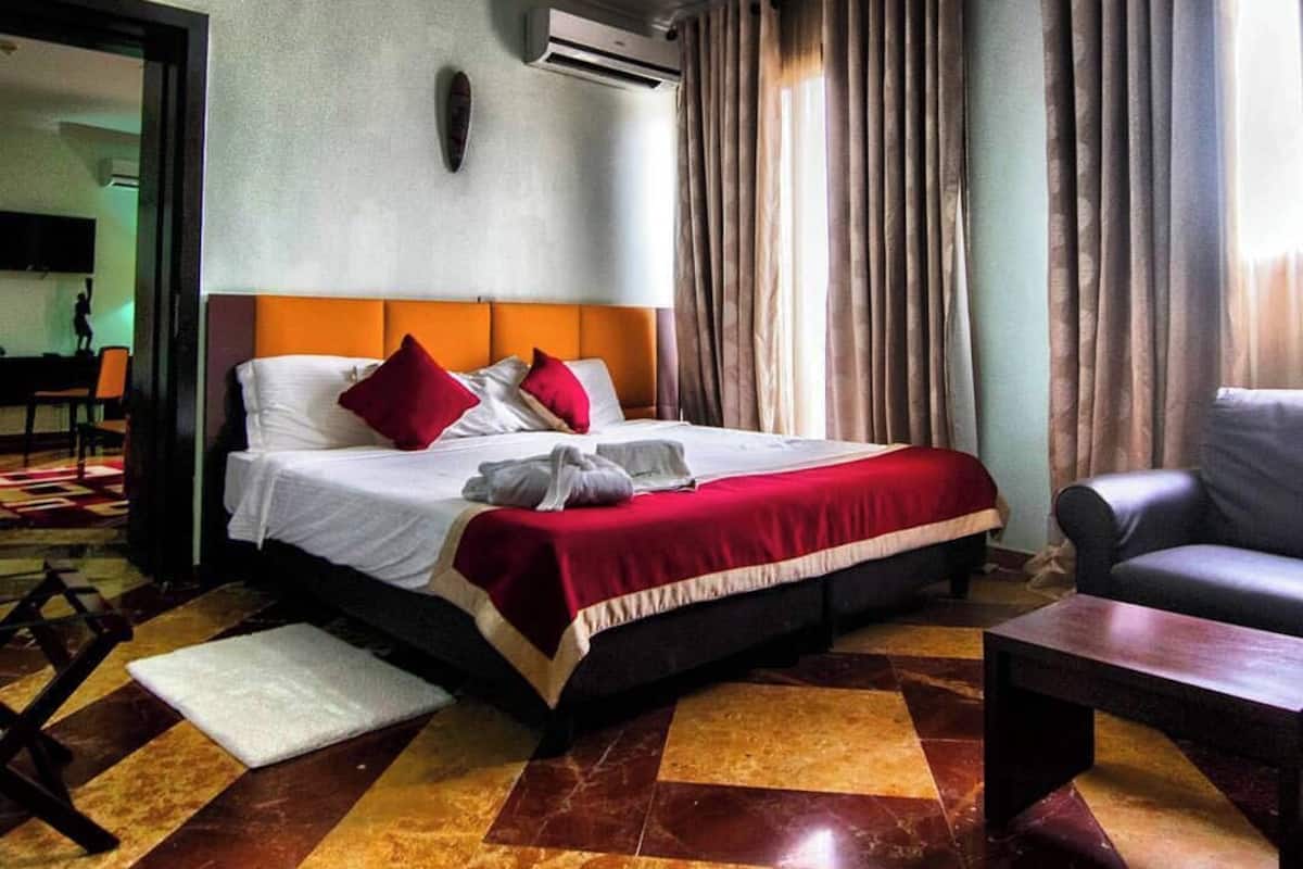 A hotel room with a bed, a chair, a small table, and a checkered floor.