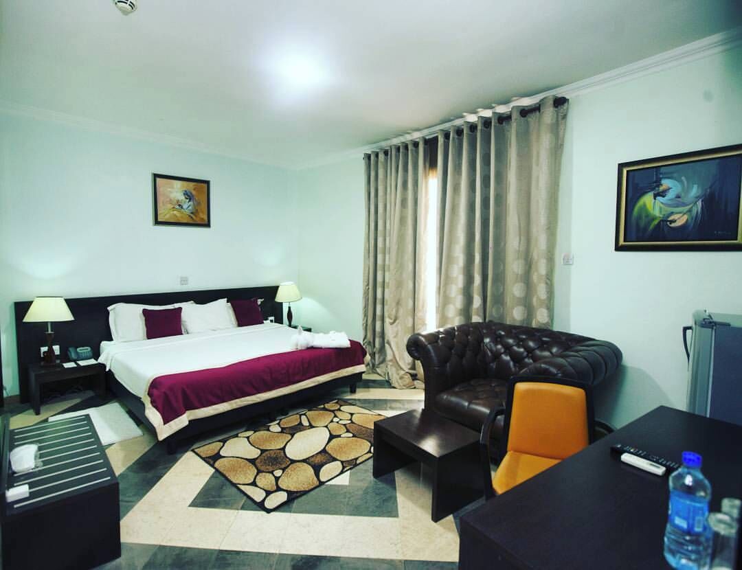 Een hotelkamer met een bed, een bank, een salontafel, een bureau en een waterfles.