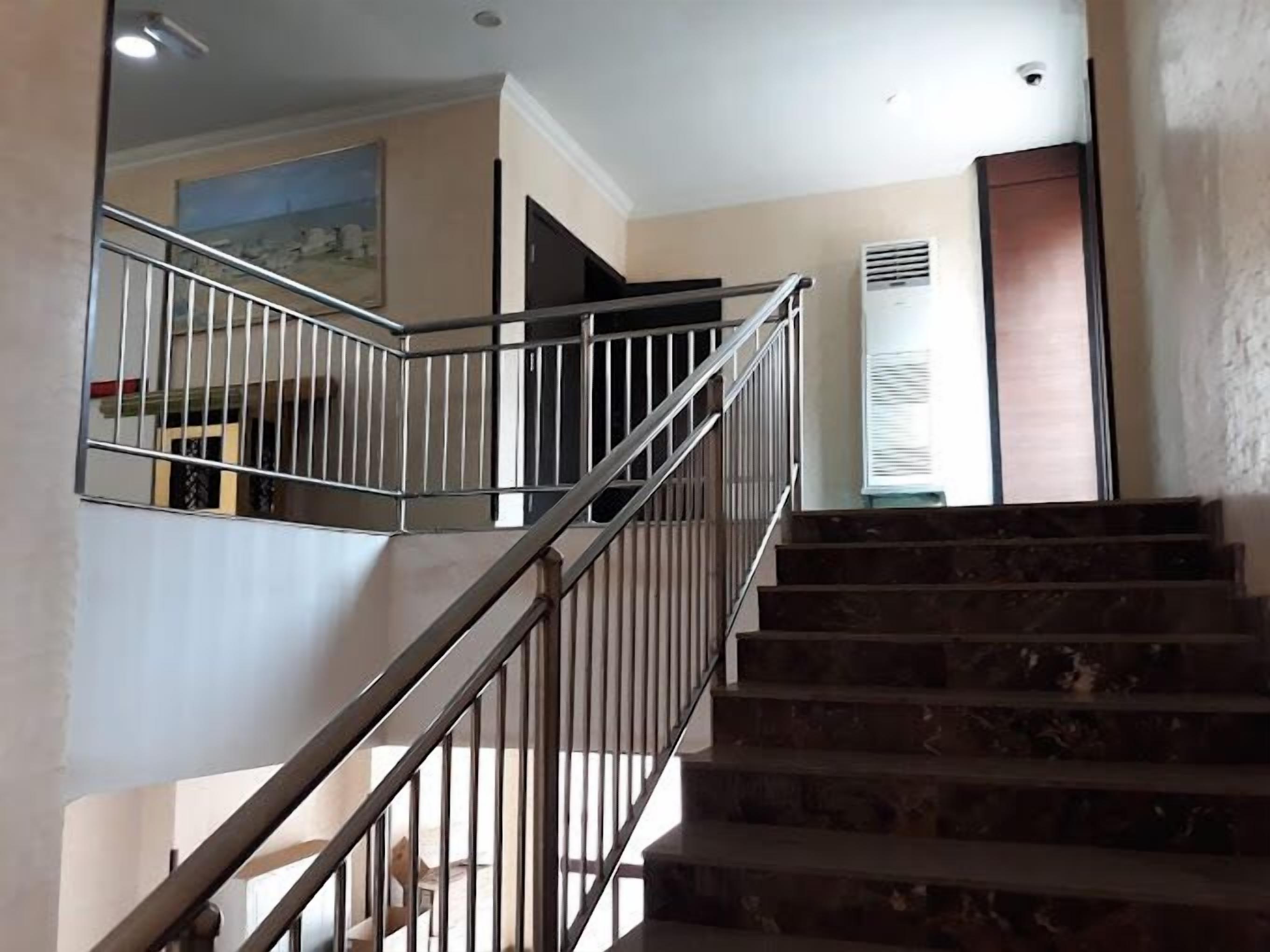 A staircase with metal railings and a handrail, leading to an upper floor.