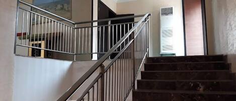 A staircase with metal railings and a handrail, leading to an upper floor.