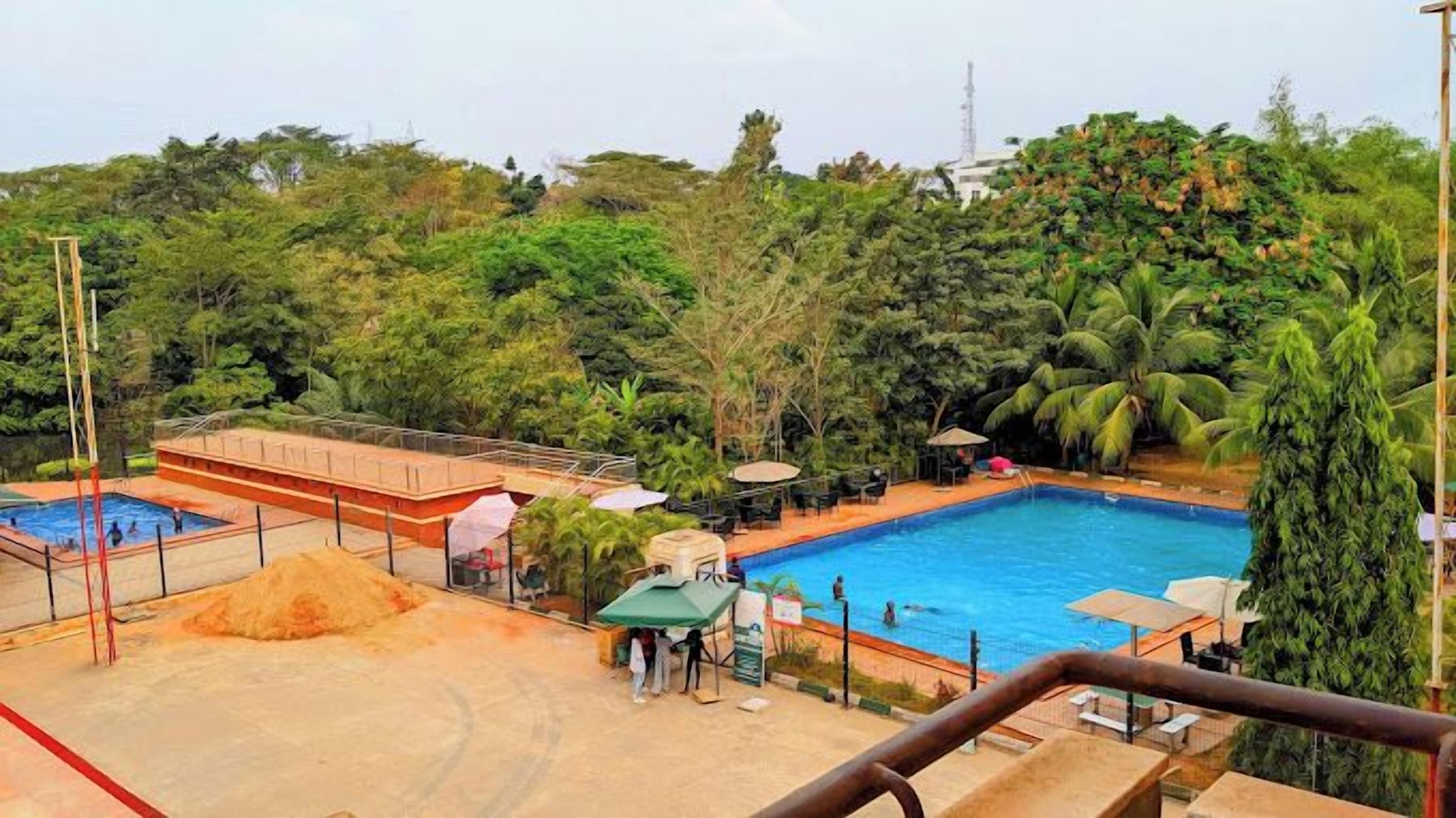A pool area with two pools, surrounded by lush greenery and palm trees.