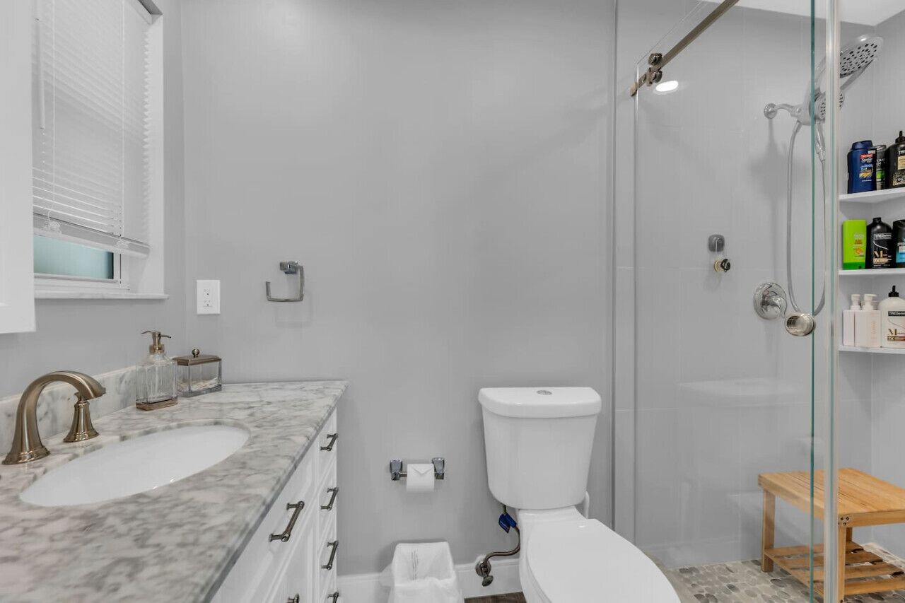 A bathroom with a marble sink, a toilet, and a glass shower enclosure.