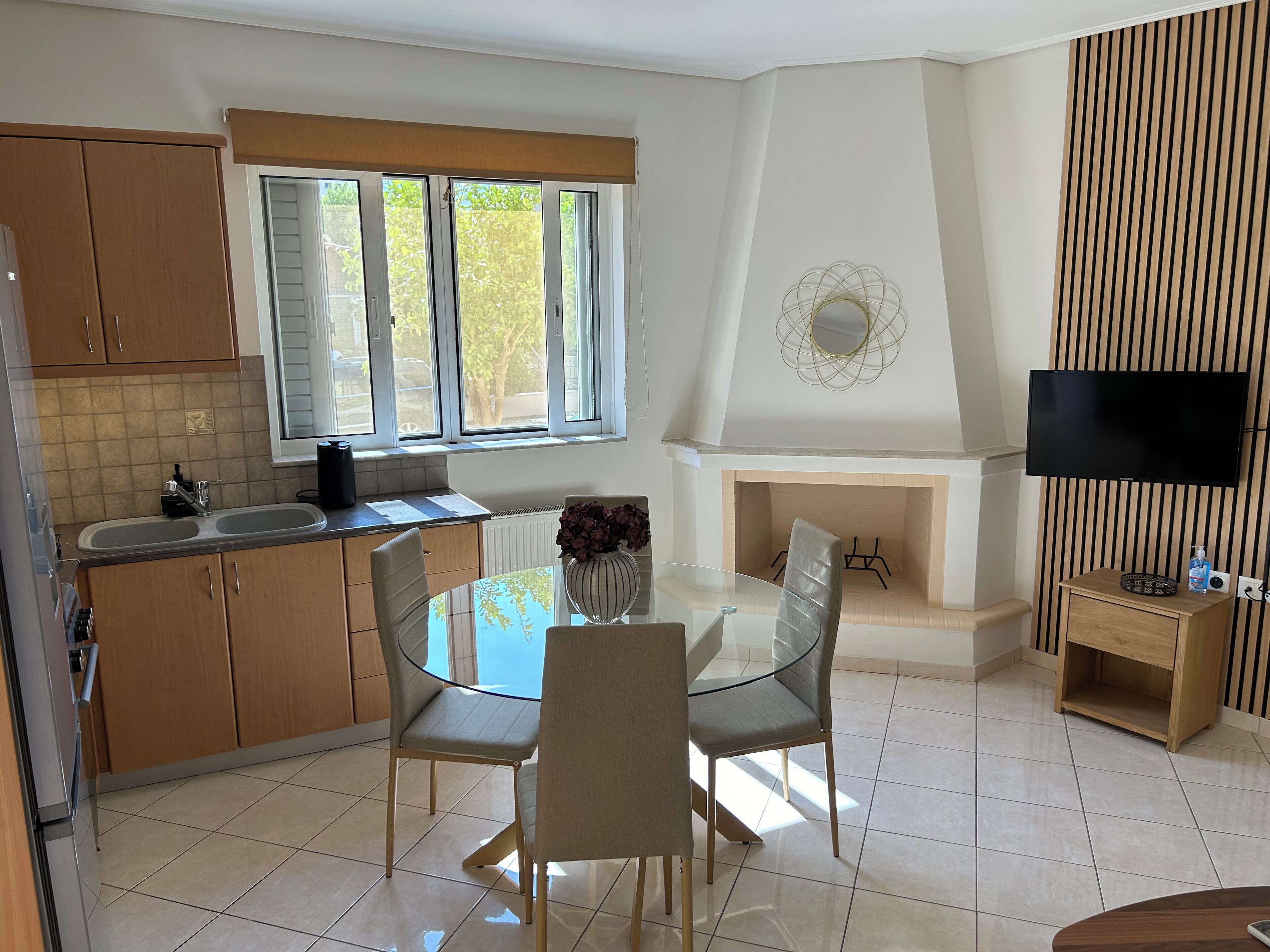 A modern kitchen with a dining area, a fireplace, and a TV.