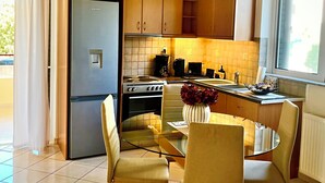 Una cucina moderna con zona pranzo, che include un frigorifero, un piano cottura e un tavolo da pranzo in vetro con sedie.