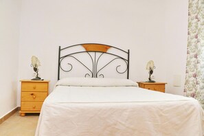 A bedroom with a bed, two nightstands, and a floral curtain.