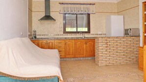 A kitchen with wooden cabinets, a brick backsplash, a white refrigerator, and a window with a curtain.