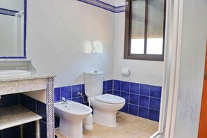A bathroom with a toilet, bidet, and sink.