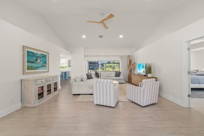 A spacious living area with a sofa, armchairs, a TV, and a ceiling fan. - Beach, Please! | East Rocks Oasis with Pool and Short Walk to the Beach! (Sanibel)