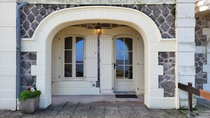 A building entrance with a stone facade, an arched doorway, and a small potted plant. - Magnifique vue Pleine mer à la Perle Marine - La Terrasse (Dinard)