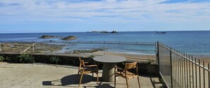A seaside patio with a round table and two chairs, overlooking the ocean and rocky outcrops. - Magnifique vue Pleine mer à la Perle Marine - La Terrasse (Dinard)
