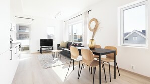 Un salon moderne comprenant un canapé, un téléviseur, une table à manger et des chaises.