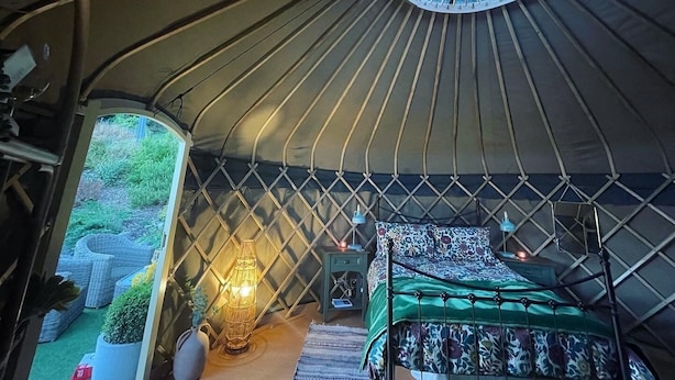 En ombonad inredning med en säng, en lampa och utsikt genom ett runt fönster.