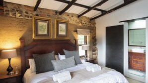 Ein stilvoll eingerichtetes Schlafzimmer mit Steinwand, Holz Kopfteil und zwei gerahmten Bildern.