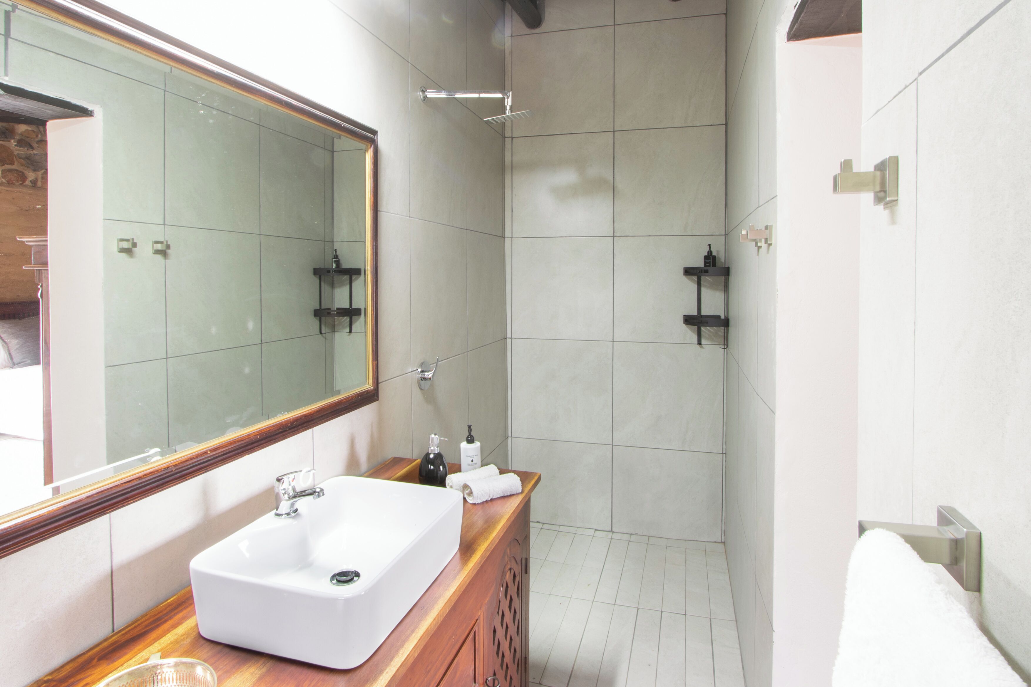 A modern bathroom with a large mirror, a white sink, and a shower area.