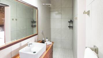 Une salle de bain moderne avec un grand miroir, un lavabo blanc et un espace douche.