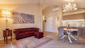 Ein modernes Wohnzimmer mit einem roten Sofa, einem gemusterten Teppich, einem Esstisch mit Stühlen und einer Pendelleuchte.