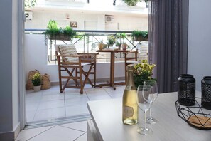 Uma varanda com mesa, cadeiras, uma garrafa de vinho e objetos decorativos.